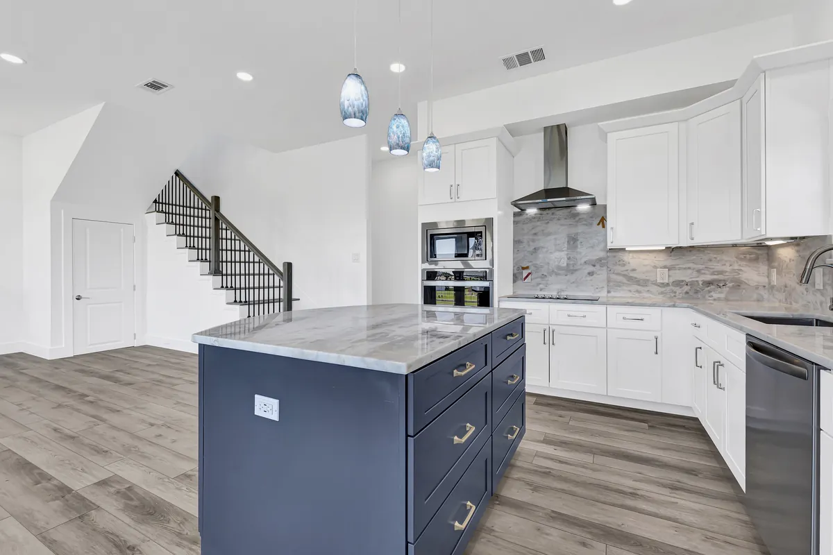 Open-concept kitchen remodel with navy island, white shaker cabinets, and marble-look quartz countertops