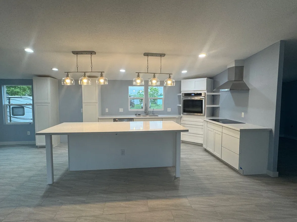 Kitchen remodel with oversized quartz island, white shaker cabinets, gray walls, and tile flooring