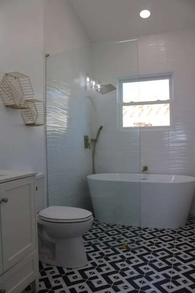 Freestanding tub and glass shower over black-and-white geometric floor tile