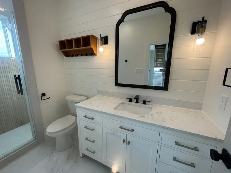 White shaker vanity with arched black mirror and shiplap walls