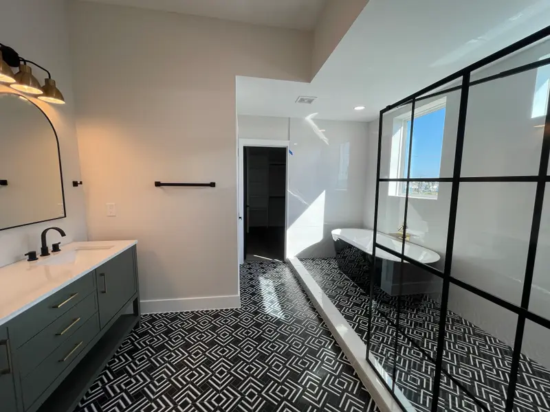 Primary bathroom with black-grid glass shower wall and patterned floor tile