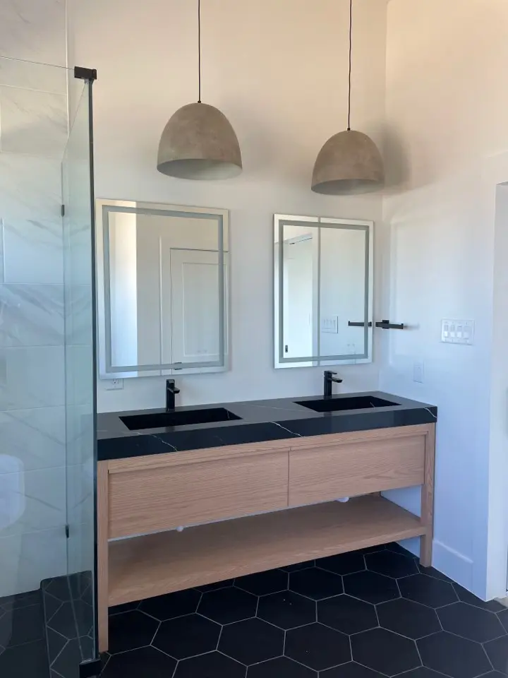 Floating double vanity with black countertops and pendant lights