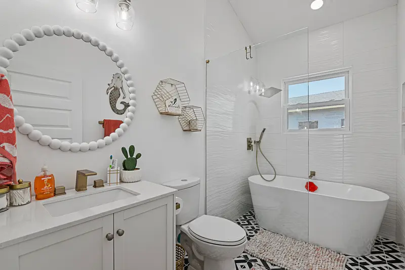 Freestanding soaking tub with round mirror and white vanity