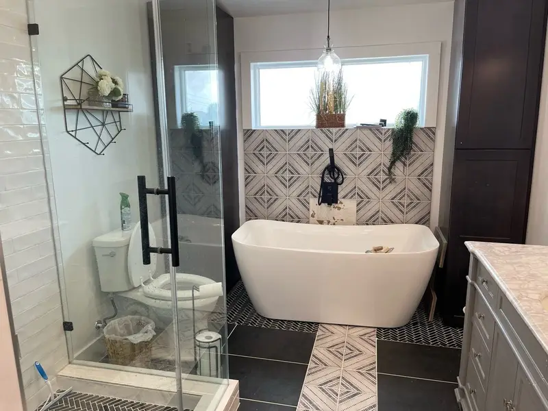 Freestanding tub with patterned tile accent wall and glass shower