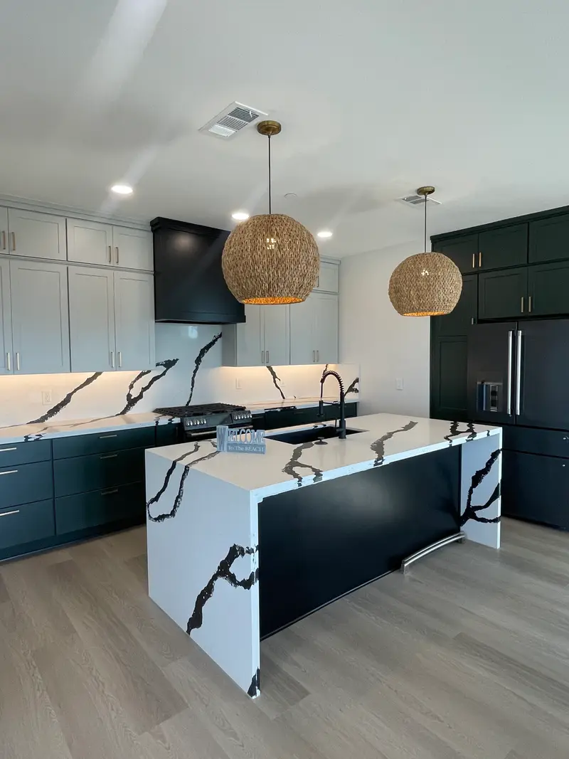 Kitchen remodel with black shaker cabinets, waterfall quartz island, and woven pendant lights