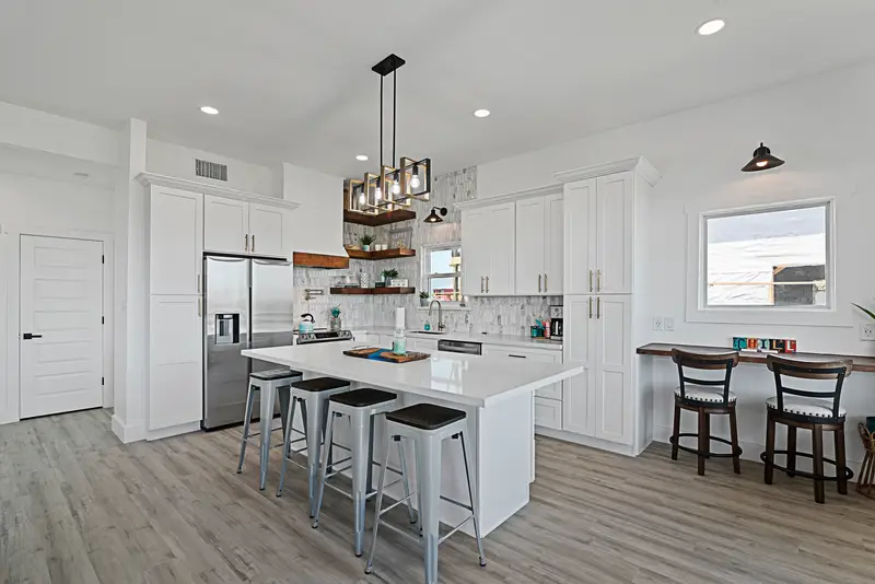 White farmhouse kitchen remodel with island seating, open shelving, and pendant lighting