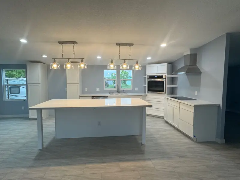 Kitchen remodel with large white quartz island, pendant lights, and white cabinets